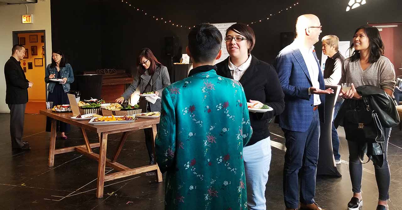 Group of people standing, eating and talking at a group event