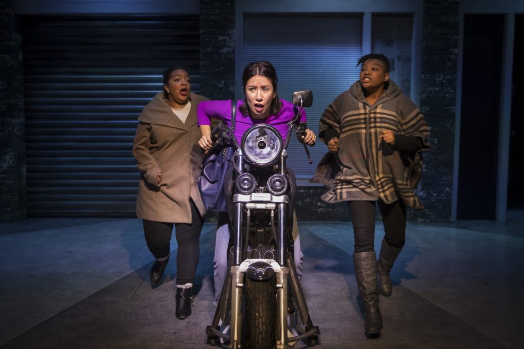 Sasha Smith and LaKecia Harris running next to a motorcycle that Monica Orozco is riding